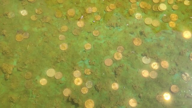 underwater treasure with shiny ancient gold coins on the background of a lucky fountain or shipwreck under the surface of the water with waves - background for a pirate story