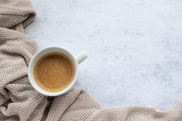 Cup of coffee cappuccino, and beige sweater on table background. Cozy beige autumn, fall aesthetic....