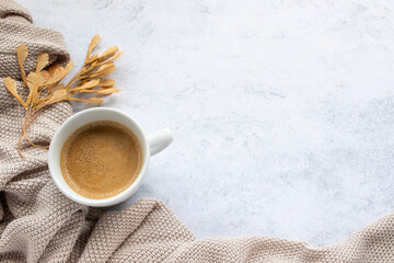 Cup of coffee cappuccino, beige sweater and dry autumn maple seeds on table background. Cozy beige...