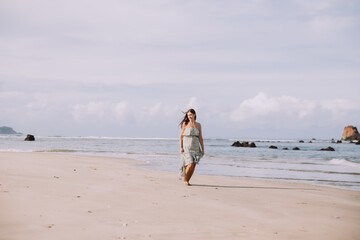 Young woman in dress running alone on the beach in tropical nature.