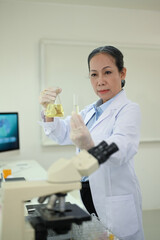 Professional senior female researcher preparing and analyzing microscope slides, conducting research investigations in laboratory