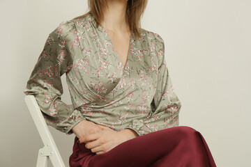 Serie of studio photos of young female model silk satin floral blouse with simple burgundy midi...
