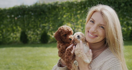 Portrait of a pregnant woman with puppies in her hands, standing in the backyard of the house