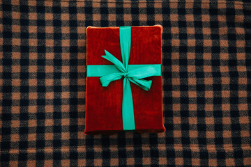 Eco friendly fabric gift box with green bow on wool clothes background. Top view