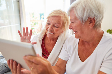 Seniorin winkt glücklich in die Webcam am Tablet Computer