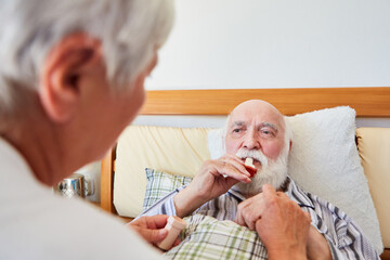 Senior im Krankenbett benutzt ein Asthma Spray