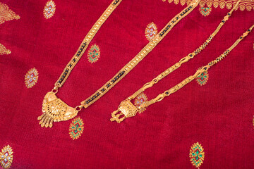 Mangalsutra or Golden Necklace to wear by a married hindu women, arranged with traditional saree with haldi, kumkum and flowers on plate. - obrazy, fototapety, plakaty