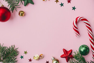Christmas flat lay. Stylish christmas festive decorations, confetti, fir branches frame on pink background. Creative seasons greeting card, space for text. Merry Christmas and Happy Holidays!