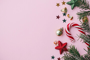 Merry Christmas and Happy Holidays! Stylish christmas festive decorations, confetti, fir branches on pink background flat lay. Creative holiday banner. Seasons greeting card, space for text