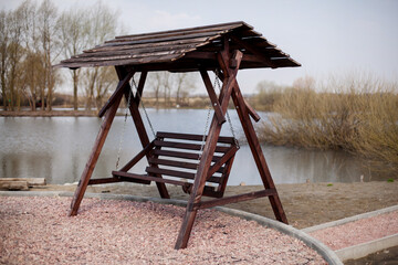 Wooden gazebo swing on the lake