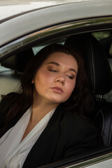 Young business woman in a black suit sitting in a car