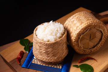 Asian Food concept Glutinous rice or Sticky rice in bamboo wicker on wooden board and black...