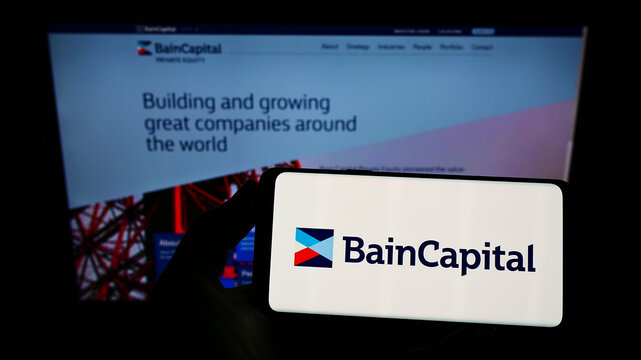 Stuttgart, Germany - 12-12-2021: Person holding smartphone with logo of US investment company Bain Capital L.P. on screen in front of website. Focus on phone display.