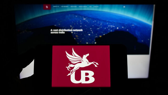 Stuttgart, Germany - 12-12-2021: Person holding cellphone with logo of company United Breweries Holdings Limited (UBHL) on screen in front of webpage. Focus on phone display.