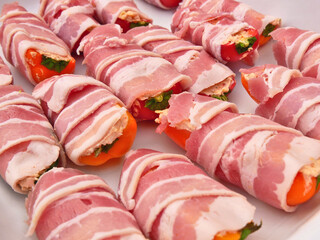 Preparation of a dish called Jalapeno poppers, composed of jalapeno peppers stuffed with cheese, sopasco and rolled with a slice of smoked bacon.