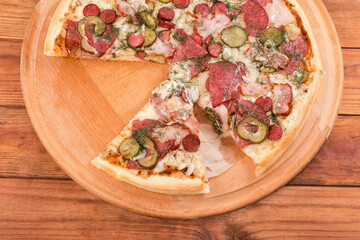 Slices of pizza with sausages on pizza board, top view