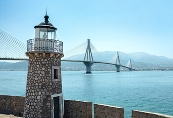 Fototapeta na wymiar Antirrio Lighthouse against modern cable stayed bridge Rio Antirrio Bridge, Greece