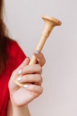 cropped photo of female doctor obstetrician in red medical suit is holding a wooden Pinard stethoscope for listening to baby heart sound. Motherhood and healthcare concept