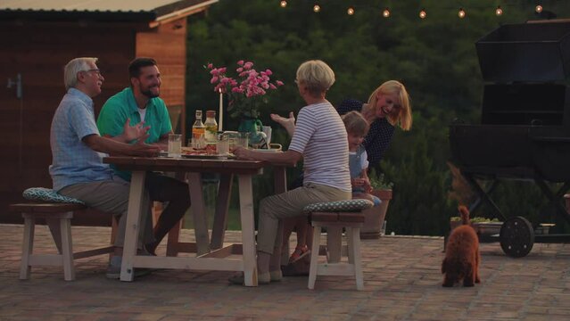 Cheerful family enjoying a family dinner outside at home during evening