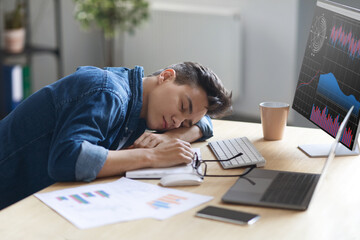 Portrait Of Tired Young Male Employee Sleeping At Work