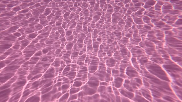 Underwater background, glare of sunlight on the bottom of the pink pool. Natural pink background with sunbeams at the bottom of the pool.  