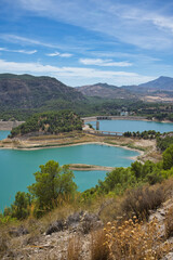 Spectacular panoramic views of the Guadalhorce reservoir, next to the Caminito del Rey in Malaga, Spain. Turquoise blue water and forest with blue sky on a sunny day.