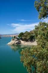 Spectacular panoramic views of the Guadalhorce reservoir, next to the Caminito del Rey in Malaga, Spain. Turquoise blue water and forest with blue sky on a sunny day.