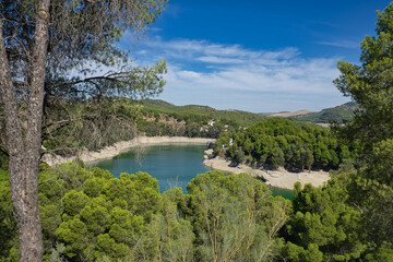 Obraz premium Spectacular panoramic views of the Guadalhorce reservoir, next to the Caminito del Rey in Malaga, Spain. Turquoise blue water and forest with blue sky on a sunny day.