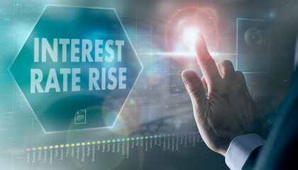 A businessman controlling a futuristic display with a Interest Rate Rise business concept on it.