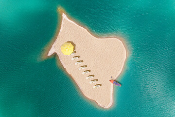 A lot of deck chair with umbrella and sup board on a small uninhabited, desert sand island  in the...