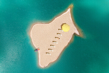 A lot of deck chair with umbrella and sup board on a small uninhabited, desert sand island  in the...