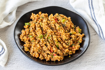 Bulgur salad on a stone background. An appetizer prepared with bulgur and green vegetables. Traditional Mediterranean cuisine delicacies. Local name kisir salatasi. close up