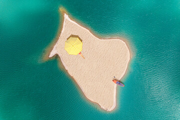 Woman sunbathes under umbrella and sup board on a small uninhabited, desert sand island  in the...
