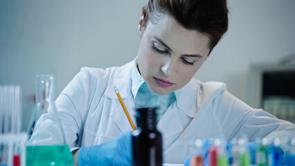 pretty scientist writing down result of analysis in laboratory.