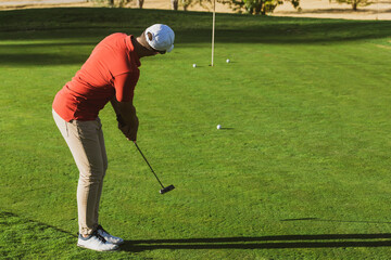 golfer practicing putter technique, alignment, grip and stance on the putting green at the golf driving range. Golf practices. Golf putter stroke to the hole. golfer hitting training putt in the hole