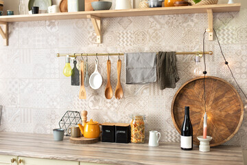 Stylish scandi cuisine interior decor. Ceramic plates, dishes, utensils and cozy decor on wooden shelfs. Kitchen wooden shelves with various ceramic jars and cookware. Open shelves in the kitchen.	
