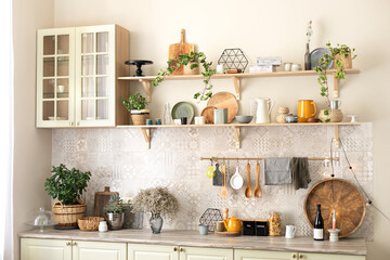 Stylish scandi cuisine interior decor. Ceramic plates, dishes, utensils and cozy decor on wooden shelfs. Kitchen wooden shelves with various ceramic jars and cookware. Open shelves in the kitchen.	