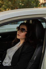 Fototapeta na wymiar Young business woman in a black suit sitting in a car