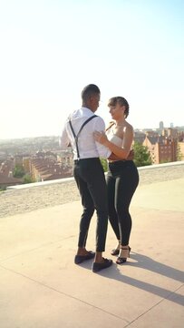 Full body dancers doing bachata moves in the street. Attractive African American man and Caucasian woman doing dance moves outdoors. Slow motion video. 