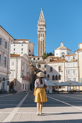 Rear View Of Young Woman Standing In Square Of Idyllic Town Of Piran, Slovenia