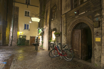 Fototapeta na wymiar Bicycles parked on empty medieval street in old city of Innsbruck at night, Tirol, Austria