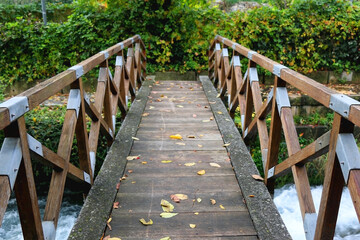 Obraz premium Small rustic bridge crossing the river and colorful autumn leaves. Beautiful autumnal landscape.
