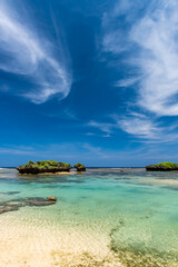 Beautiful crystal clear turquoise sea waters forming natural pools between coral rocks, blue sky.