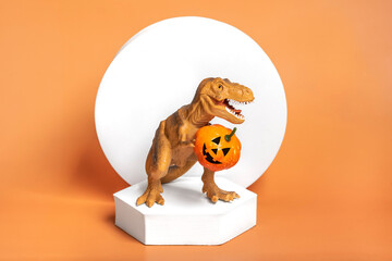Toy dinosaur Tyrannosaurus holding pumpkin in its paws, on white podium isolated on orange background Holiday greeting card Happy Halloween day, Hello Autumn creative minimal concept