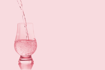 Pink liquid drink in glass isolated on pink background.