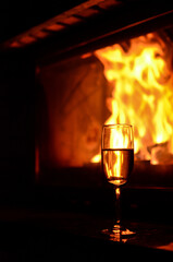 Champagne glasses full of bubbly champagne on the table by the burning flames of a fireplace
