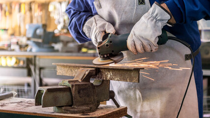 Metal processing with a man using angle grinder to cleaning the steel seam.