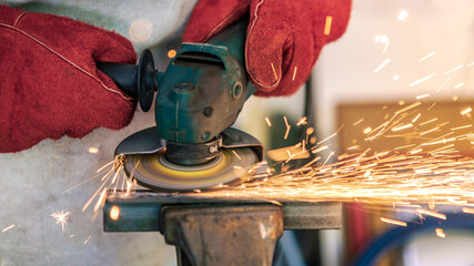 Craftsman grinding metal with disk grinder in workshop. Worker cleaning a steel