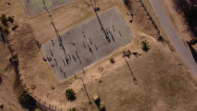 A dynamic aerial shot moving above the handball court with players under training. Handball is a team sport where players pass a ball using with the aim of throwing it into the goal of the other team.