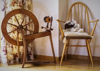 Old Fashioned Wool Spinning Wheel. Pictured in a bright craft room. Vintage tailoring equipment...
